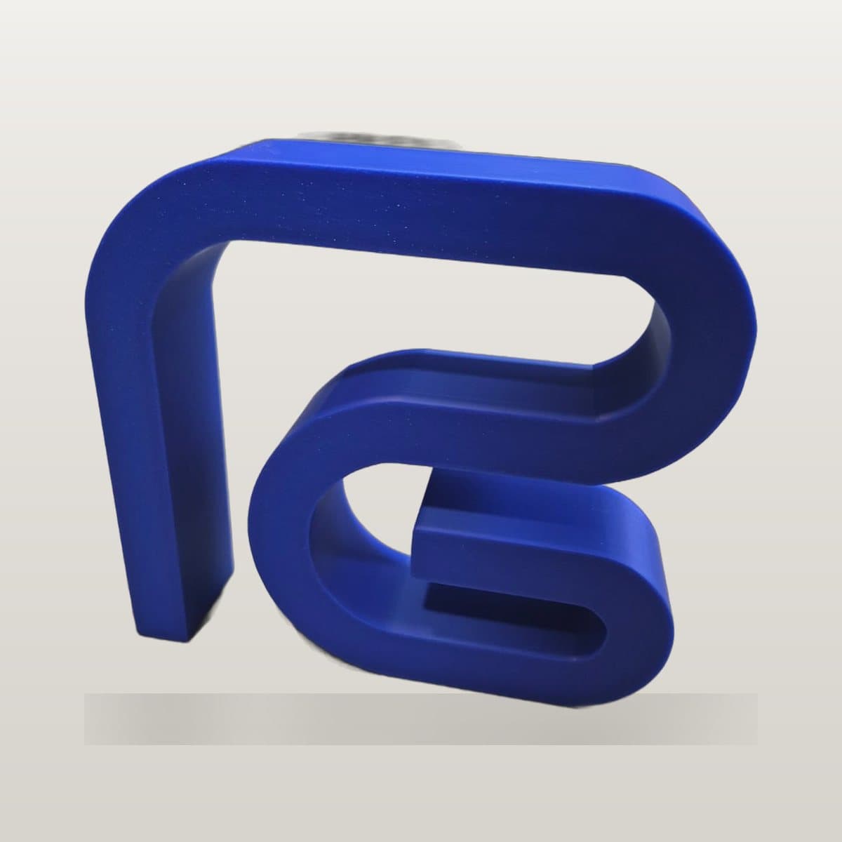 Blue 3D printed monogram of a physiotherapy clinic's logo, standing on a surface